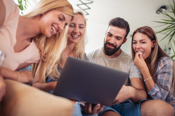 Smiling friends looking at laptop together