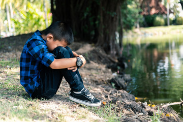 Little asian child sitting and waiting someone at frontwater. Depressed asian boy. Young asian boy sad