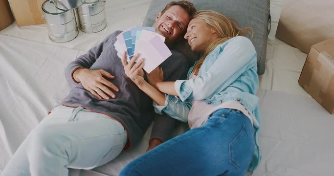Happy young couple looking at paint options together, kissing smiling, new homeowners, home improvement