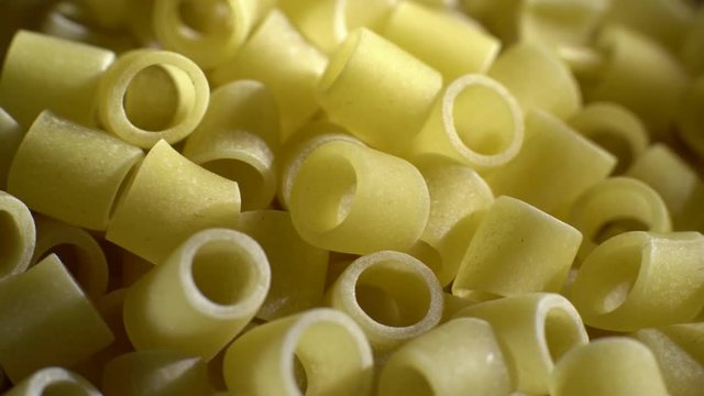 Raw macaroni in rotation. Ditalini lisci. Close up.  Raw pasta, Italian cuisine concept.