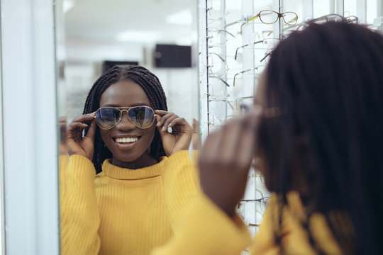 Young pretty african woman try sunglasses in optical store