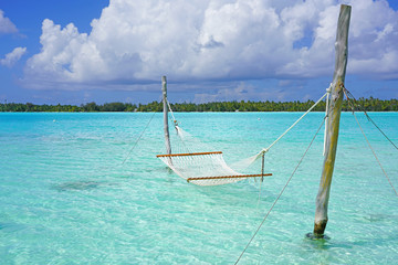 Hammock with a view, planted in the azure waters of the Bora Bora lagoon, French Polynesia  - obrazy, fototapety, plakaty