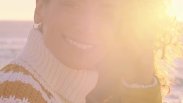 close up portrait of beautiful happy woman enjoying freedom exploring spirituality feeling joy on peaceful beach at sunset with wind blowing hair