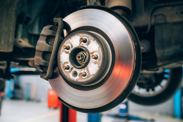 Close up of car disc brake during the wheel tire change or repair. Disc brake of the car during the maintenance at auto service garage.  - obrazy, fototapety, plakaty