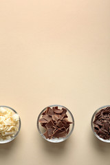Bowls with different chocolate curls and space for text on color background, top view