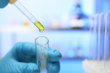 Laboratory assistant dripping urine sample from pipette into test tube, closeup with space for text. Medical analysis
