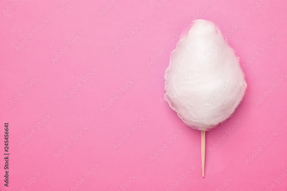 Wall mural Stick with yummy cotton candy on color background, top view. Space for text