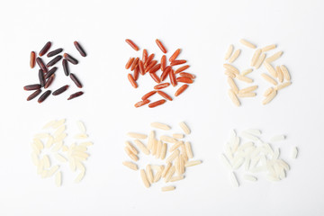 Different types of uncooked rice on white background, top view