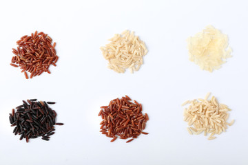 Different types of uncooked rice on white background, top view