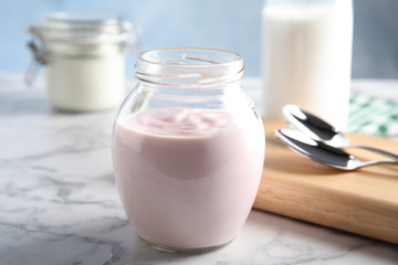 Glass jar of fresh yogurt on table
