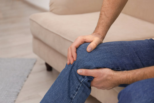 Senior man suffering from knee pain at home,closeup. Space for text