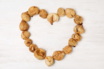 Heart shaped frame made of dried figs on wooden table, top view with space for text. Healthy fruit