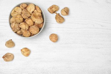 Bowl of dried figs on wooden table, top view with space for text. Healthy fruit