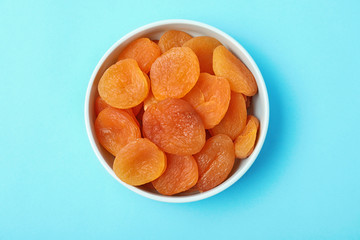 Bowl with dried apricots on color background, top view. Healthy fruit