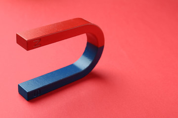 Red and blue horseshoe magnet on color background. Space for text