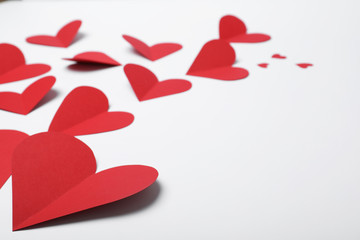 Many red paper hearts on white background