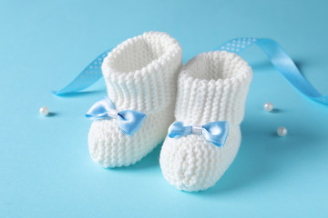 Fototapeta na wymiar Handmade baby booties with bows on color background