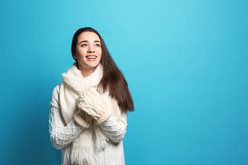 Obraz premium Young woman wearing warm clothes on color background, space for text. Winter season