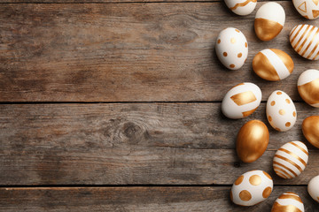 Fototapeta na wymiar Traditional Easter eggs decorated with golden paint on wooden background, top view. Space for text