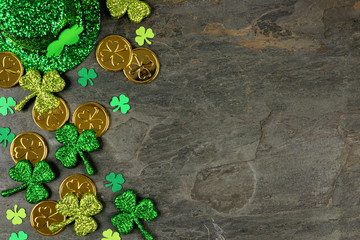 St Patricks Day side border with shamrocks, gold coins and leprechaun hat over a dark slate...