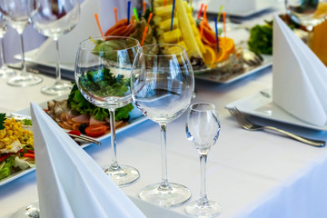 Served dishes to the table for holiday. Cutlery and food on white tablecloths in the restaurant. Design a festive Banquet. Luxurious food for guests and visitors.