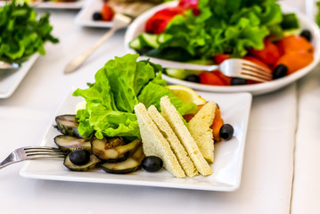 Served dishes to the table for holiday. Cutlery and food on white tablecloths in the restaurant. Design a festive Banquet. Luxurious food for guests and visitors.