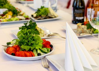 Served dishes to the table for holiday. Cutlery and food on white tablecloths in the restaurant. Design a festive Banquet. Luxurious food for guests and visitors.