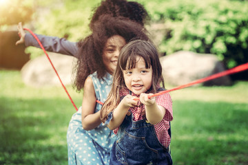 Happy children playing tug of war and having fun during summer camping in the park. Children...