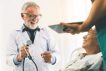 Mature doctor talking and examining health of senior patient in hospital ward. Medical healthcare...