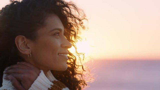 portrait of beautiful hispanic woman enjoying peaceful seaside at sunset exploring mindfulness contemplating spirituality with wind blowing hair