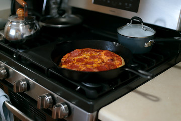 Freshly baked homemade pepperoni pizza in cast iron pan from the oven.
