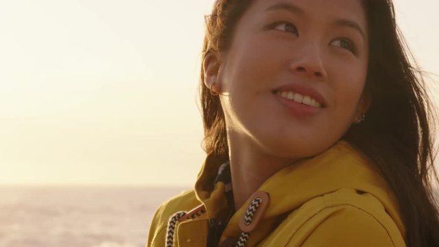 portrait of beautiful asian woman enjoying seaside at sunset exploring spirituality looking up praying contemplating journey relaxing on beach