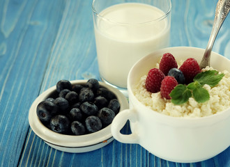 Cottage cheese with berries, waffles and milk on a wooden blue background. Top view.