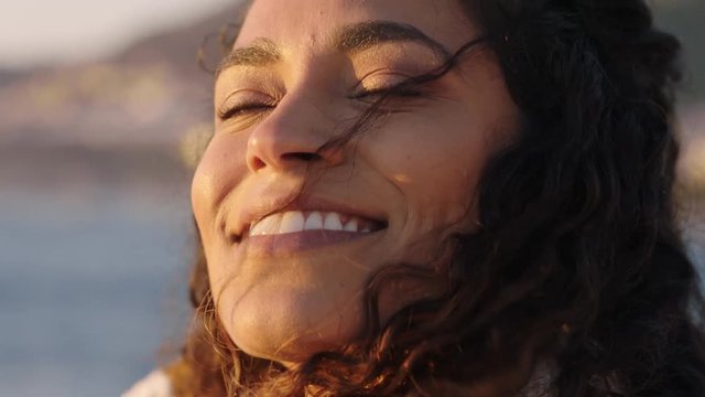 close up portrait of beautiful happy woman enjoying freedom exploring spirituality feeling joy on peaceful beach at sunrise with wind blowing hair