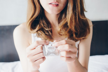 Cropped shot view of woman open the condom wrapper before using with her partner. Safe sex and...
