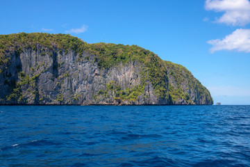 Fototapeta na wymiar Tropical island in still sea. Palawan island seascape. Philippines travel photo. Black rock mountain with wild green forest