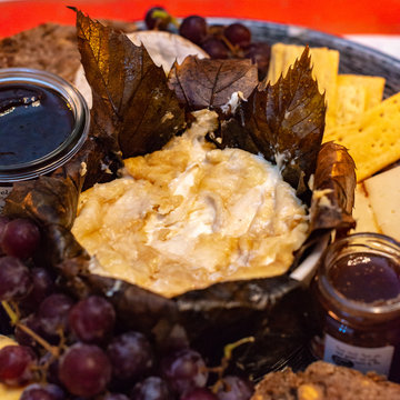 Dessert cheese plate with Castagnino Italian Goat Robiola soft cheese in Chestnut Leaves served with jams and grapes