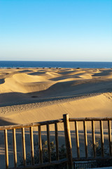 Landscape with yellow sandy dunes of Maspalomas and blue Atlantic ocean, Gran Canaria, Spain