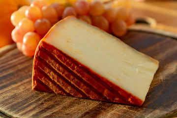 Spanish goat milk cheese with paprika coating and ripe pink table grapes
