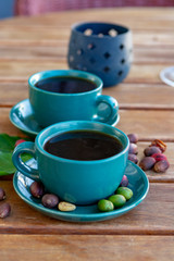 Cup with black coffee served outside with raw green, mature red and roasted coffee beans, decorated with green leaves from coffee plant