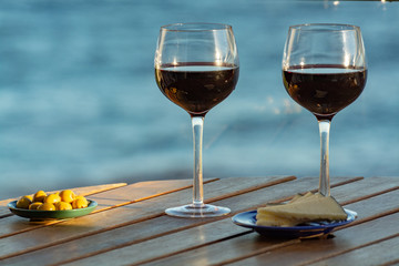 Aperitif, red wine in glasses served with cheese and olives on outdoor tessace witn sea view