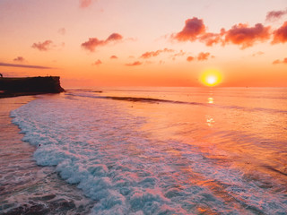 Aerial view of ocean with waves, surfers and sunset in Bali