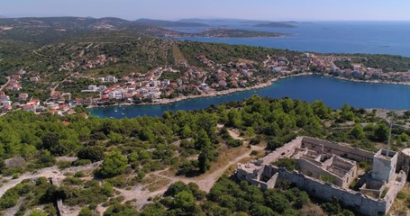 Mediterranean coast, C4k aerial, drone shot, bypassing old ruins, on the top of a hill, overlooking small razanj town and the croatian shore, at the adriatic sea, on a summer day, in Croatia