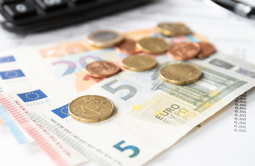 Banknoten auf einer Rehnung mit einem Taschenrechner im Hintergrund