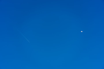 An airplane flying in the sky and half moon appear.