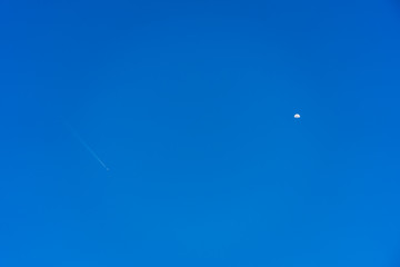 An airplane flying in the sky and half moon appear.