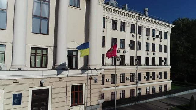 The facade of the administrative building in the old style with the flag of Ukraine in front of it