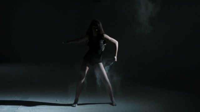 Caucasian girl wearing black leotard performing edgy contemporary dance moves