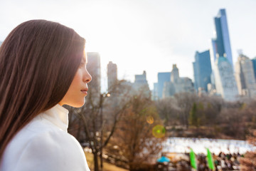 New York City Asian woman walking in winter in Central Park by the skating rink pensive looking at...