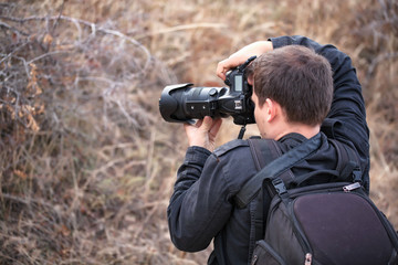 man with a camera on the nature takes something